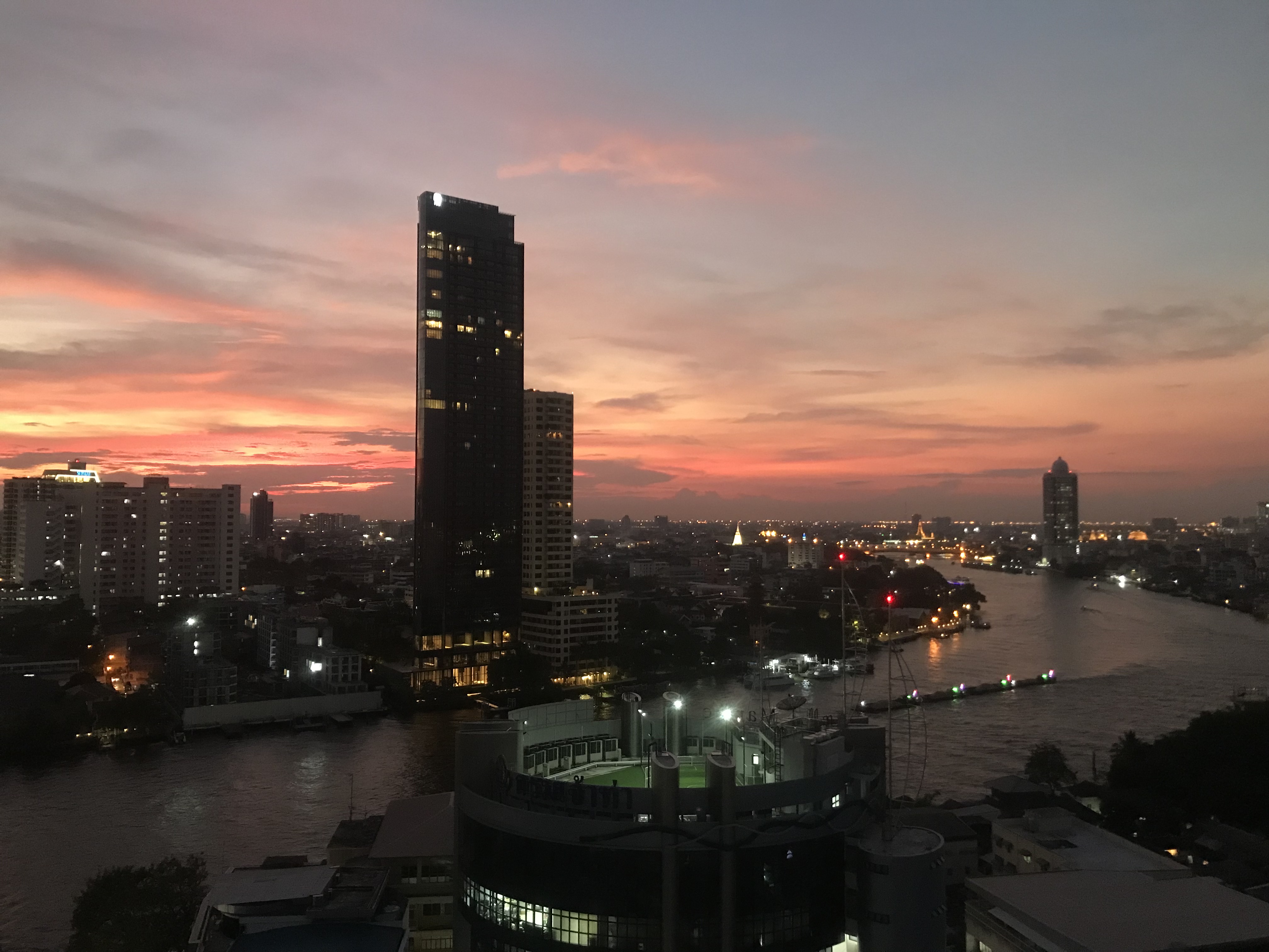 夕陽映照曼谷塔拉特諾伊一帶的湄南河，河岸建築與船隻形成城市河景