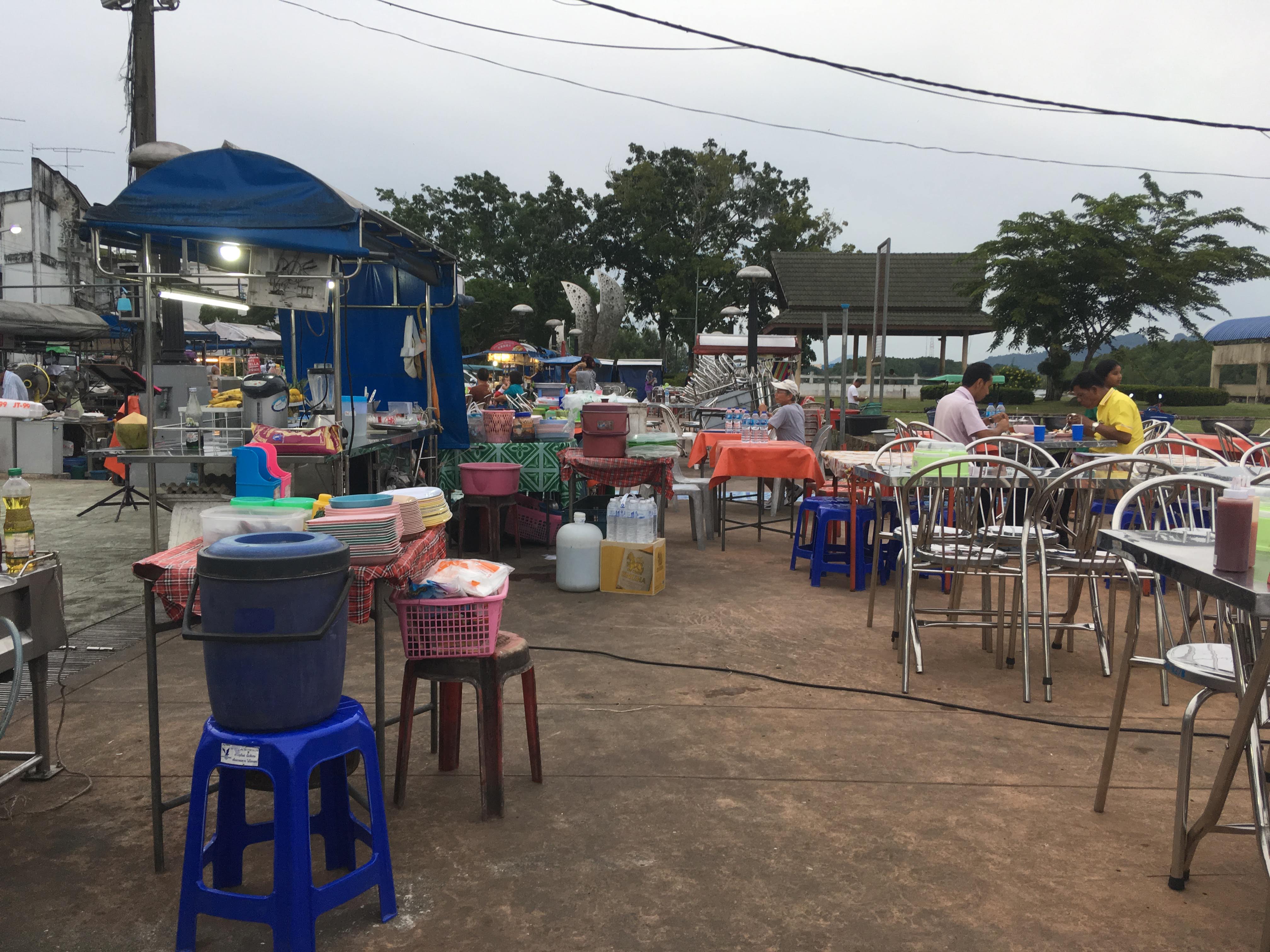 喀比鎮河岸市集旁的攤販和餐桌，呈現鎮區用餐情境