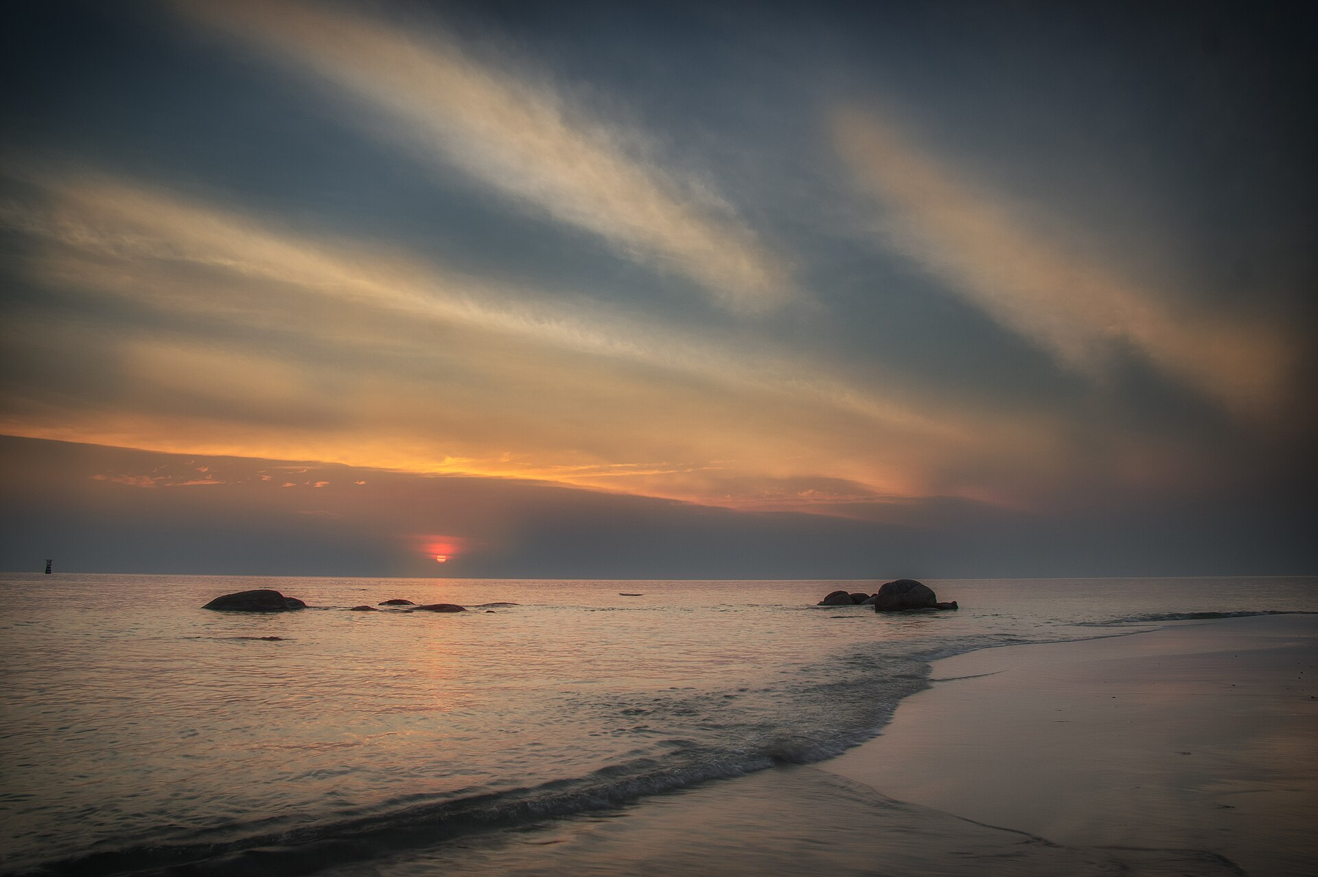 華欣公共海灘日出時的海面、岸邊礁石與沙灘，作為地區景觀背景，並非瑞享阿薩拉飯店或別墅實景
