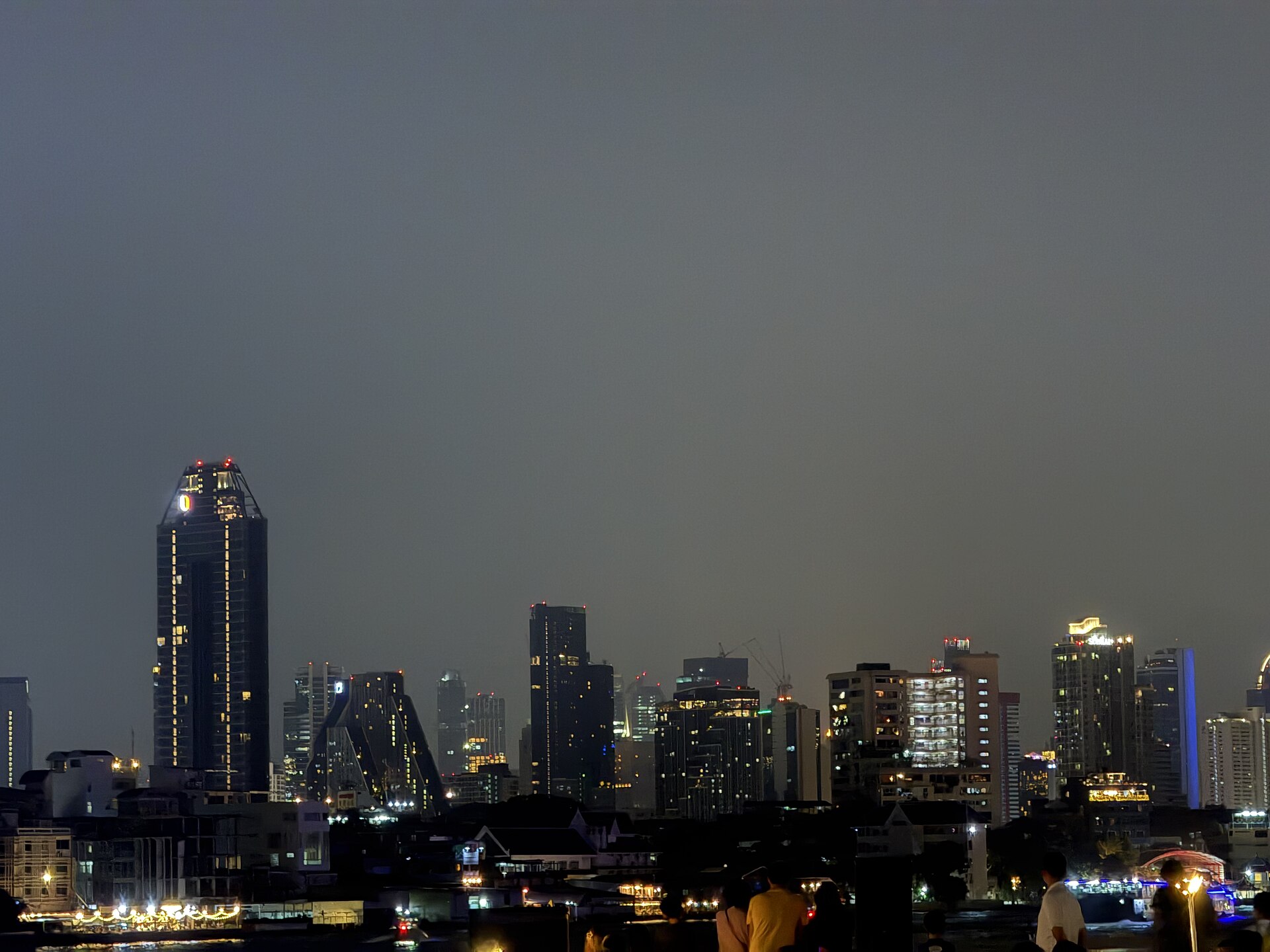 曼谷市區高樓夜景，前景樓宇燈光映在夜色中，作為城市夜間氛圍示意，並非任一飯店實景