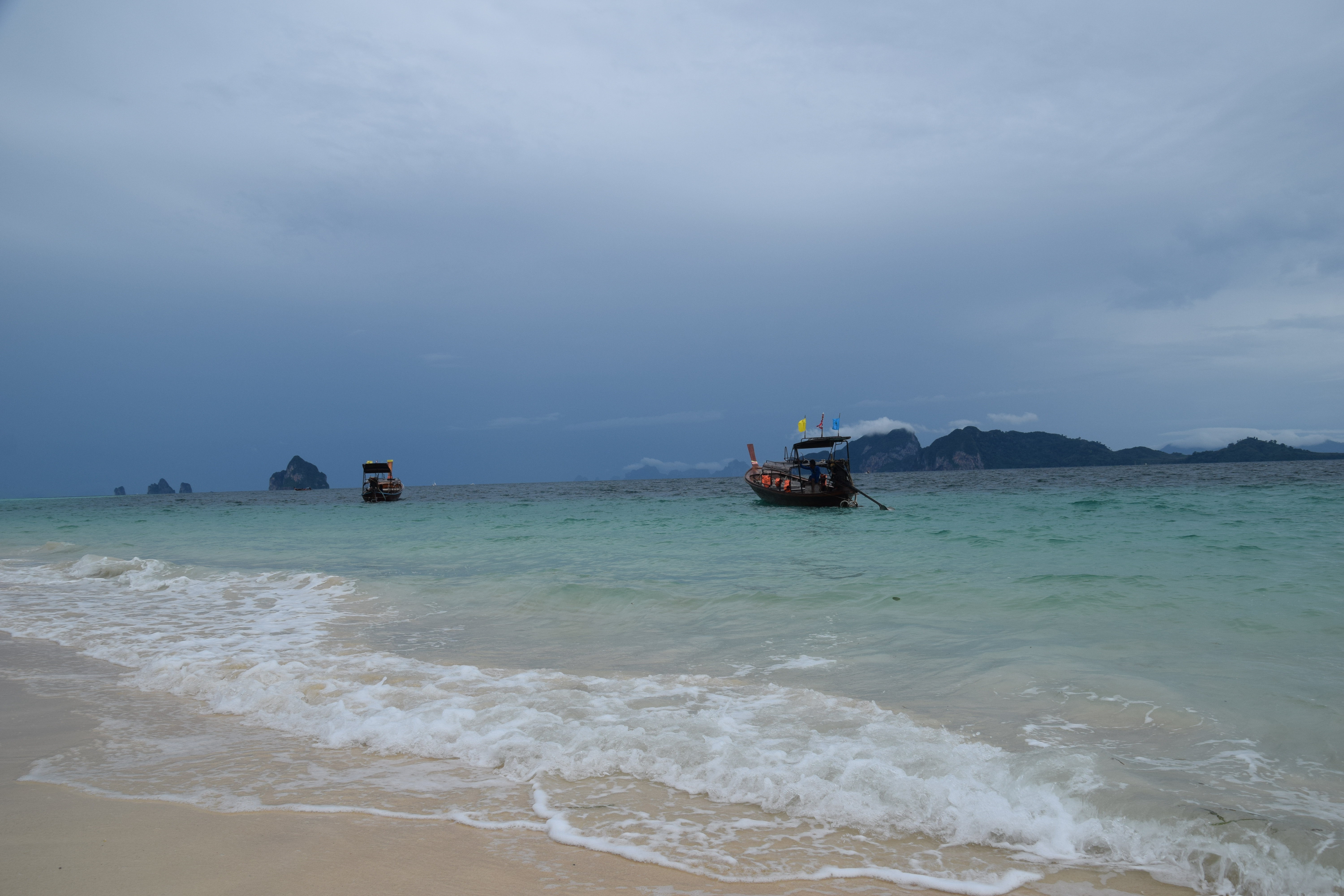 克拉丹島海灘與淺藍海水,近海停泊著長尾船